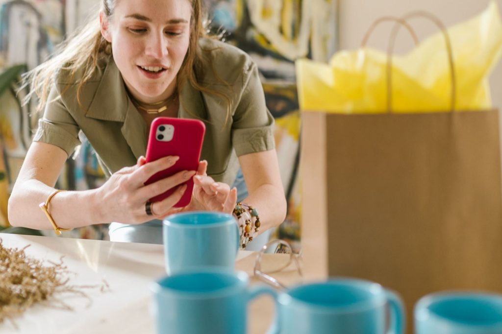 Small business owner photographing her mugs with her phone